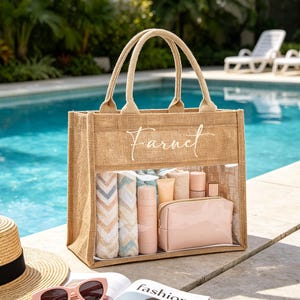 May include: A rectangular jute tote bag with two top handles and a clear plastic front panel. The word Farnet is printed in white script on the upper jute section. Inside the bag are rolled patterned towels, bottles, and a pink pouch.