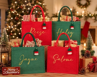 May include: Four rectangular tote bags in red and green with gold cursive names Reese, Haley, Jayne, and Salome printed on the front. Each bag features two matching fabric handles and a small decorative tassel charm hanging from one handle.