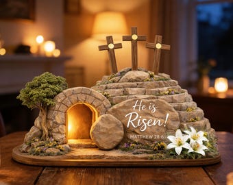 May include: A decorative Easter scene featuring three wooden crosses atop a stone structure with the text "He is Risen!" and a stone entrance. The scene includes a small tree, flowers, and a large stone in front of the entrance.