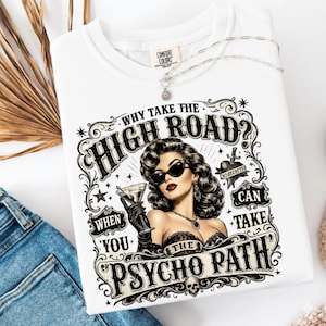 Op de afbeelding: Wit Comfort Colors T-shirt met een afbeelding van een vrouw met een zonnebril die een martini vasthoudt. De tekst luidt: "Waarom de hoge weg nemen? Als je het psycho pad kunt nemen."