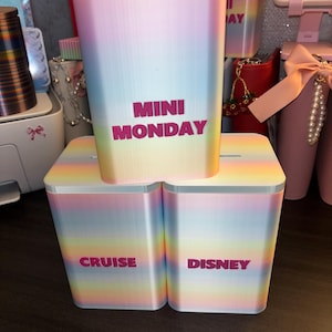 May include: Three rectangular pastel rainbow-coloured containers with white lids. The top container features the text MINI MONDAY in pink. The bottom left container displays the text CRUISE, and the bottom right container displays the text DISNEY.