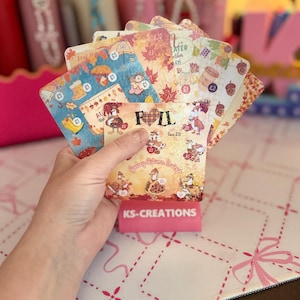May include: A fan of rectangular savings challenge cards featuring autumn-themed illustrations of geese, leaves, and umbrellas. The cards display text including FALL, Goosey Autumn Savings, and KS-CREATIONS, with various pound currency symbols.