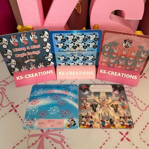 May include: Five square savings challenge cards featuring Disney characters Mickey and Minnie Mouse. The cards display various scratch-off icons, including hearts, bows, and fireworks, with text labels like Mickey & Minni Magic Savings and KS-CREATIONS.