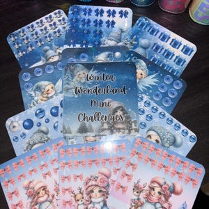 May include: A selection of Winter Wonderland Mini Challenges cards with diverse designs. The cards showcase illustrations of snowmen, gift boxes, bows, and girls with reindeer. The colour scheme includes blue, pink, and white, with text reading "Winter Wonderland Mini Challenges".