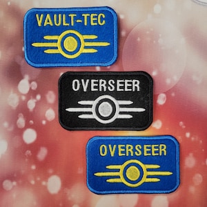 May include: Three embroidered patches. One blue patch reads "VAULT-TEC" with a yellow and white emblem. A black patch reads "OVERSEER" with a white and grey emblem. A blue patch also reads "OVERSEER" with a yellow and white emblem.