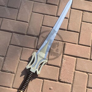 May include: A silver-bladed sword with a decorative hilt. The hilt is cream-colored with a black grip and gold accents. The sword is lying on a brick surface. The text "Highland Blades" is visible.