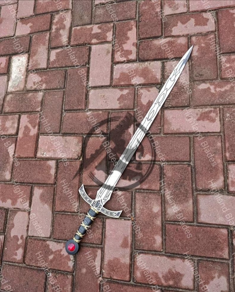 May include: A silver sword with a decorative handle featuring a black grip, gold accents, and a red gem. The blade has etched designs. The sword is lying on a brick surface.
