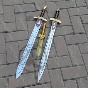 May include: Three swords with silver blades and brown handles are displayed on a brick surface. Two larger swords have a cross-shaped design on the hilt, and a smaller gold dagger is in the center. The text "Highland Blades" is visible.