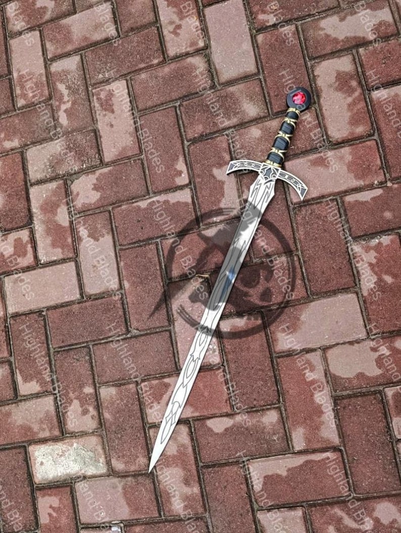 May include: A silver sword with a decorative handle featuring black and gold accents and a red gem. The blade has an intricate design and is set against a brick background.
