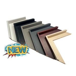 May include: A selection of picture frame corner samples in shades of white, black, grey, and wood. The frames are displayed at an angle. A graphic with the word "NEW" is in the bottom left corner.