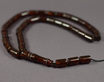 Pode incluir: Um terço castanho escuro com contas retangulares brilhantes, enfiadas num fio escuro. O design é simples e elegante, adequado para meditação ou práticas espirituais. As contas medem cerca de 1 cm de comprimento.