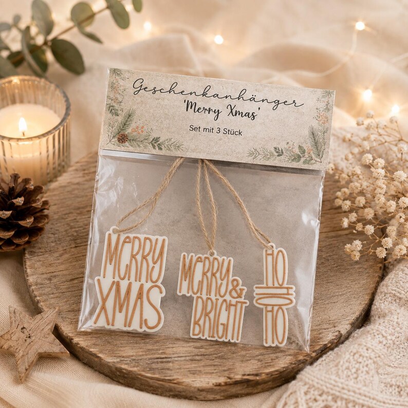 Verpacktes 3er Set Geschenkanhänger Weihnachten in Creme und Kupfer auf einem Holzteller mit Tannengrün und warmen Lichtern.