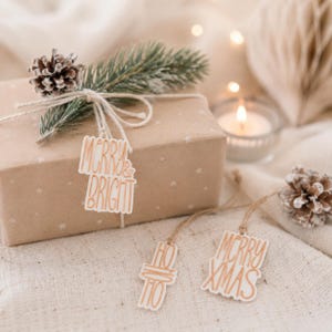 Merry & Bright Anhänger an einer natürlichen Geschenkverpackung Weihnachten, daneben Merry Xmas und Ho Ho Ho zum liebevollen Geschenke Verpacken.