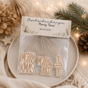 Verpacktes Set mit drei Weihnachtsgeschenke Anhängern in Creme und Kupfer als wiederverwendbare Dekoration für Weihnachten Geschenke.