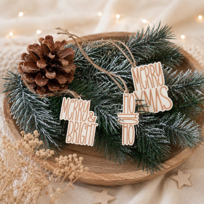Drei Weihnachtsgeschenke Anhänger in Creme und Kupfer auf Tannenzweigen mit Zapfen als stilvolle Idee zum Geschenke kreativ Verpacken an Weihnachten.