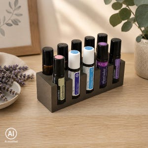 Könnte beinhalten: Ein rechteckiger, dunkelgrauer Betonständer mit acht ätherischen Öl-Roll-on-Flaschen. Die Flaschen haben schwarze Kappen und Etiketten mit Texten wie dōTERRA, Gardenia, Calmer, Rescuer, PastTense und Lavender, angeordnet in zwei Reihen.