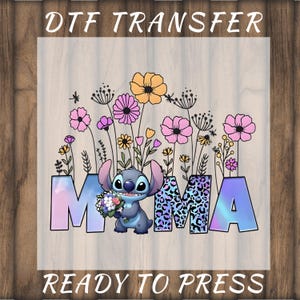 May include: DTF transfer with the word "MAMA", floral elements, and a cartoon character. The letters have a gradient effect, and the central "M" features a leopard print. The text "READY TO PRESS" is at the bottom of the design.