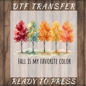 May include: A DTF transfer sheet featuring a watercolor illustration of five trees with autumn foliage in shades of red, green, orange, and yellow. The text reads DTF TRANSFER, FALL IS MY FAVORITE COLOR, and READY TO PRESS in black lettering.