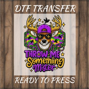 May include: A DTF transfer design featuring a deer wearing sunglasses, a purple cap, and a beaded necklace. The text "THROW ME Somethiiing Mister" is in gold and purple. The words "DTF TRANSFER" and "READY TO PRESS" are also included.