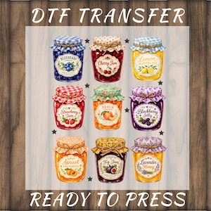 May include: DTF transfer design featuring nine jars of preserves, including blueberry, cherry jam, lemon marmalade, strawberry jam, peach, blackberry jelly, apricot preserves, fig jam, and lavender honey. The text "DTF TRANSFER" and "READY TO PRESS" are at the top and bottom.