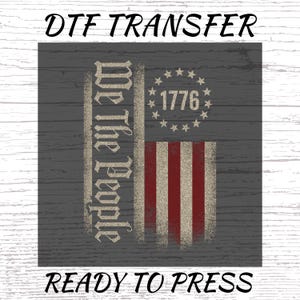 May include: DTF TRANSFER graphic with a distressed American flag design. The flag features red and white stripes, a circle of stars with the year 1776, and the text "We The People". The words "READY TO PRESS" are also included.