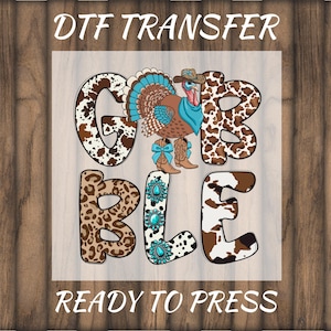 May include: DTF TRANSFER graphic with the word "GOBBLE" in a mix of cow print and leopard print. A turkey wearing a cowboy hat and boots is in the center. The words "READY TO PRESS" are at the bottom.