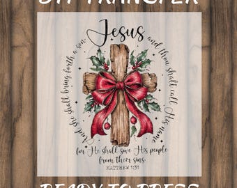 May include: DTF transfer featuring a wooden cross adorned with a red bow and holly. The words "Jesus" and a Bible verse are displayed. The text "DTF TRANSFER" and "READY TO PRESS" are also visible.
