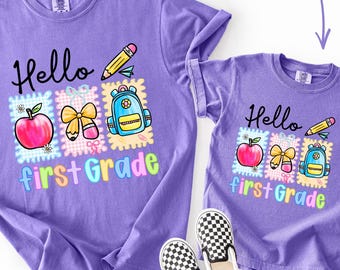 Może przedstawiać: Dwie fioletowe koszulki z nadrukiem graficznym z napisem Hello first Grade. Wzór zawiera czerwone jabłko, żółty ołówek, żółtą kokardkę i niebieski plecak na tle w kratkę. Koszulki są prezentowane wraz z butami w szachownicę.