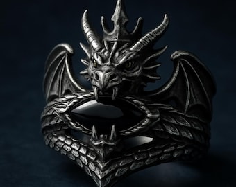 May include: A detailed silver dragon ring with a black oval stone. The dragon features intricate scales, wings, and a crown. The ring is designed with a gothic or fantasy theme.