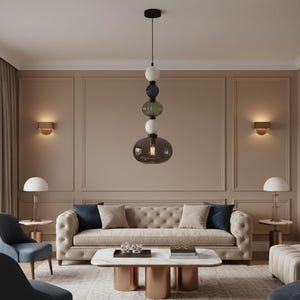 May include: A modern living room featuring a beige tufted sofa with navy and beige accent pillows. A multi-colored glass pendant light hangs above a marble-topped coffee table. Two blue chairs and two side tables with lamps complete the decor.