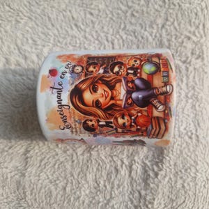 Può includere: Una tazza in ceramica bianca con un'illustrazione a cartoni animati di un'insegnante circondata da bambini e oggetti scolastici. La tazza ha il testo "Enseignante en or!" in un carattere di scrittura, con uno sfondo in stile acquerello.