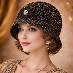 Puede incluir: Un sombrero cloche negro con detalles dorados y una flor negra decorativa con adornos de perlas. El sombrero tiene una copa redondeada y un ala inclinada hacia abajo. Estilo vintage.