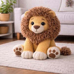 May include: A crocheted lion plush toy with a tan body, a brown mane, and a white muzzle. The lion has large, dark eyes and brown paw pads. The toy is sitting on a light-colored rug.