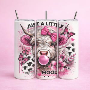 Puede incluir: Vaso blanco con un gráfico de vaca rosa, lazo rosa y mariposas. Se muestra el texto "JUST A LITTLE MOOD". Incluye una pajita plateada y una tapa rosa. El vaso está diseñado para bebidas frías.