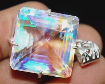 May include: A square-cut iridescent gemstone pendant set in a silver-toned metal prong setting. The stone displays a multi-colored spectrum of light reflections across its faceted surface, attached to a decorative silver-toned metal bail.