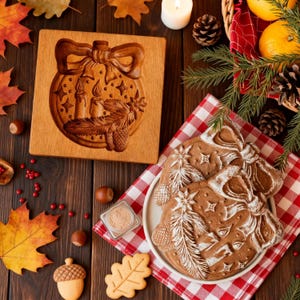 Pu&ograve; includere: Uno stampo per biscotti in legno con un design intagliato di ornamento natalizio, insieme a biscotti di pan di zenzero decorati. Il design dell'ornamento include un fiocco, candele, stelle e pigne. La scena &egrave; ambientata su un tavolo di legno con foglie autunnali e noci.