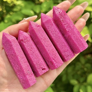 May include: A white ceramic mug with a black handle and the text "But First, Coffee" in a bold, black font. The mug is set against a blurred background, suggesting a cozy setting.