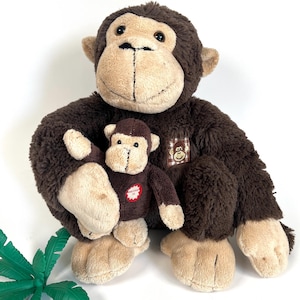 May include: Two plush monkey toys. The larger monkey is brown with tan facial features and a small patch. The smaller monkey is brown with a red tag. The toys are soft and cuddly.