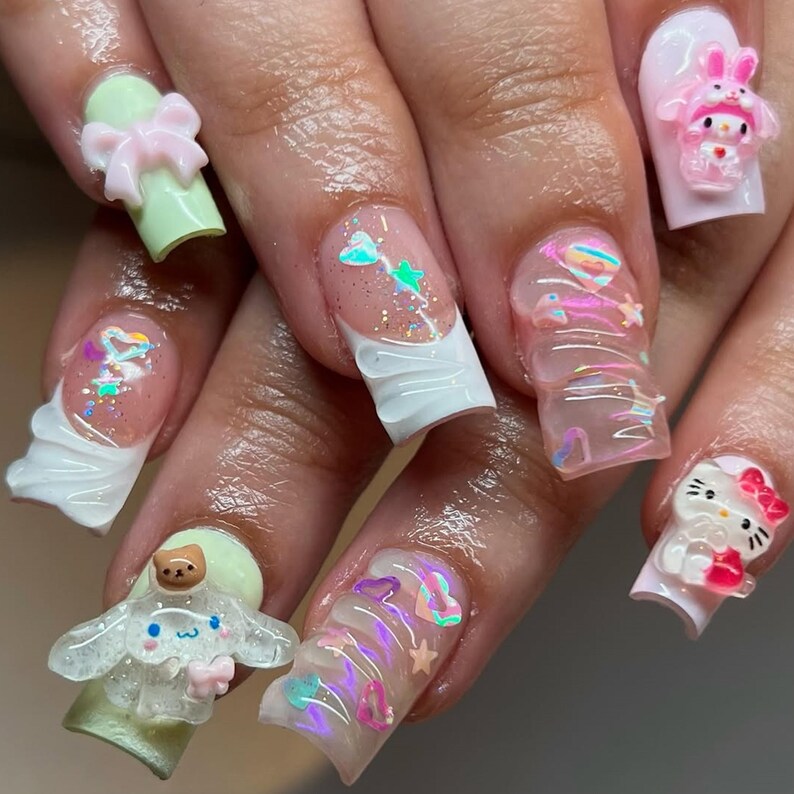 Peut inclure: Une manucure avec des ongles longs et d&eacute;cor&eacute;s. Les ongles pr&eacute;sentent divers motifs, notamment des n&oelig;uds 3D, des personnages de dessins anim&eacute;s, des paillettes et des accents iris&eacute;s. La palette de couleurs comprend le rose, le blanc, le vert et le transparent. Il s'agit d'une forme de nail art.