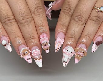 May include: A set of long, almond-shaped artificial nails with a pink and white color scheme. Each nail features 3D embellishments, including teddy bears, bunnies, bows, and hearts. Some nails have polka dots and chocolate bar accents.