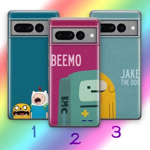 Puede incluir: Tres fundas para teléfono con diseños coloridos. Una funda es de color turquesa con personajes de dibujos animados, otra es magenta con la palabra "BEEMO", y la tercera es azul claro con "JAKE THE DOG". Cada funda tiene un recorte para la cámara y un marco metálico.