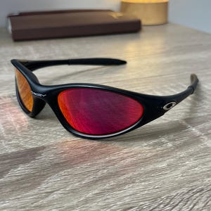 Oakley Minute 1.0: Matte Black Y2K Wrap Sunglasses – Red Iridium Oakley Minute 1.0: Matte Black Y2K Wrap Sunglasses – Red Iridium