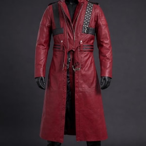 Könnte beinhalten: Ein langer, roter Ledermantel mit schwarzen Akzenten, präsentiert auf einer Schaufensterpuppe. Der Mantel hat einen Reißverschluss, Nieten an der Schulter und einen Gürtel. Die Schaufensterpuppe trägt schwarze Handschuhe und Stiefel vor dunklem Hintergrund. Ca. 140 cm lang.