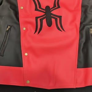 May include: Red and black jacket with a black spider emblem on the chest. The jacket has a red body with black sleeves and side panels. Features include gold-colored snap closures and zippered pockets.