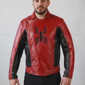 May include: A red and black leather jacket with a unique spider emblem on the chest. The jacket features a button closure and black panels on the sides and sleeves. The jacket is a stylish outerwear piece.