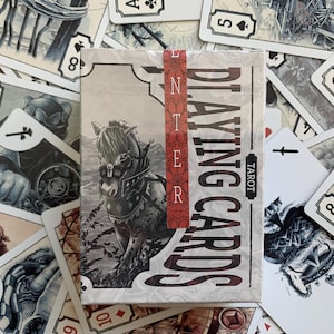 Op de afbeelding: Een kaartspel "ENTER PLAYING CARDS TAROT" met een paardenillustratie op de doos, omringd door individuele speelkaarten. De kaarten hebben een vintage esthetiek met gedetailleerde illustraties en een neutraal kleurenpalet.