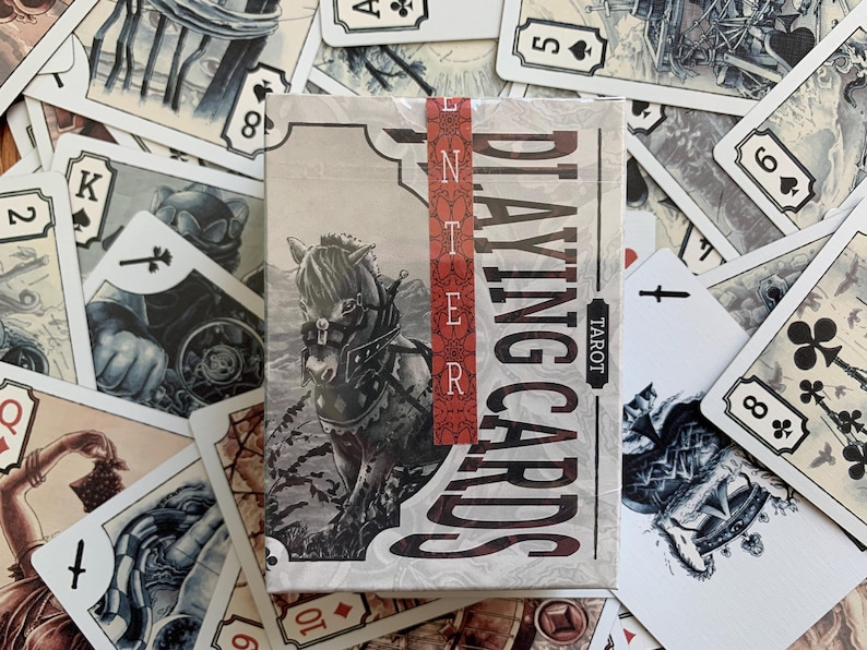 Op de afbeelding: Een kaartspel "ENTER PLAYING CARDS TAROT" met een paardenillustratie op de doos, omringd door individuele speelkaarten. De kaarten hebben een vintage esthetiek met gedetailleerde illustraties en een neutraal kleurenpalet.