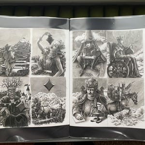 以下が含まれることがあります： 白黒イラストが掲載された開いた本。丘を登る人、ブドウを食べる人、車椅子に乗った人など、詳細なシーンが描かれています。アートワークは詳細です。