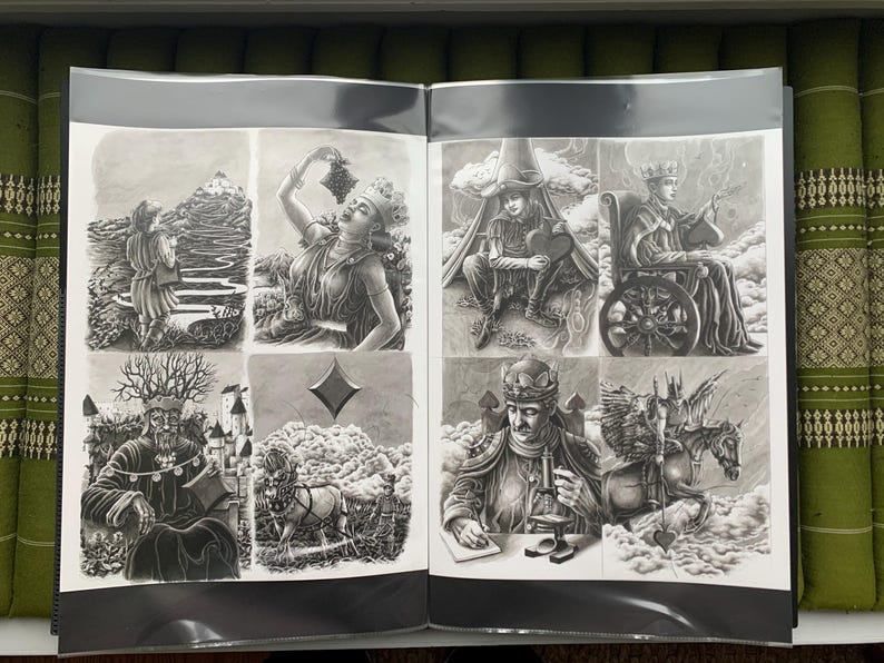 以下が含まれることがあります： 白黒イラストが掲載された開いた本。丘を登る人、ブドウを食べる人、車椅子に乗った人など、詳細なシーンが描かれています。アートワークは詳細です。