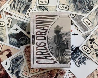 May include: A deck of playing cards titled "The Cards Drawn" with a grayscale illustration of a person. The cards are scattered around the box, featuring various suits and numbers. The overall aesthetic is vintage and artistic.